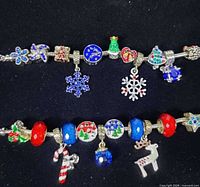 Overview of two assembled charm bracelets displaying various Christmas themed charms and beads