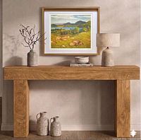 Framed lithograph displayed on wooden console for scale