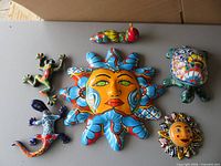 All six Talavera ceramic pieces laid out: large sun, frog, worm, turtle, small sun, lizard