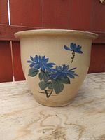 front view of tan ceramic planter with blue flowers