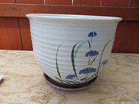 front view of ribbed white ceramic planter with blue flowers and attached saucer