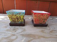 Both square planters on saucers, front view