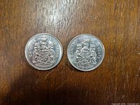Reverse view of both coins displaying coat of arms and dates