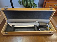 Saber in open wooden display box showing full blade and case interior