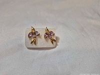 Front view of both earrings on backing showing floral design and purple stones