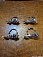 Set of four silver-plated eggplant napkin rings on wooden surface