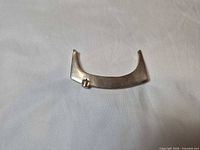 Front view of curved silver-tone pendant showing bezel-set clear stone