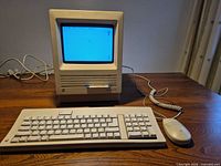 Macintosh SE with keyboard, mouse and power cable displayed on desk