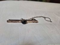 Front view showing bar, black cabochon, chain and loop