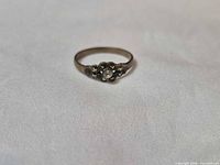 Front view of silver floral cluster ring showing gemstone and floral motif