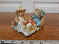 Full view of figurine showing both teddy bears, tea set, quilt base, and scale ruler
