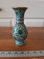 Full side view of cloisonné vase beside ruler