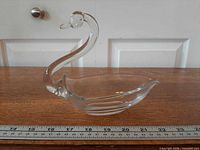 Left profile of clear glass swan candy dish beside ruler showing length