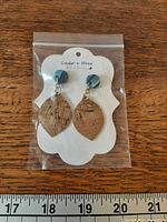 Front view of packaged earrings next to ruler