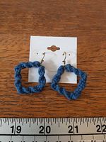 Front view of blue macrame earrings on card beside ruler
