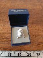 Thimble inside open presentation box with ruler for scale