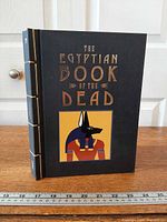 Front view of hardcover showing title, Anubis illustration, and exposed stitched spine