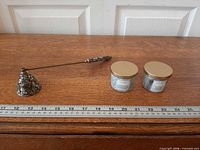 Full view of brass snuffer and two candles with ruler for scale