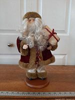 Full view of Santa figure on wood base with ruler for scale