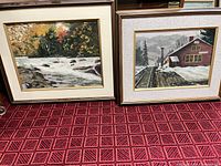 Both framed paintings standing side by side on carpet