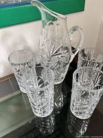 Pitcher and four tumblers on glass table
