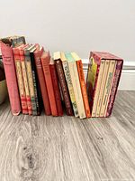 Row of vintage red cloth and mixed paperback books on floor