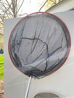 Full view of large landing net with red rim and damaged mesh
