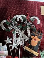 Wreath components, candy-cane picks, star toppers, red ornament picks, wooden reindeer sign on red surface