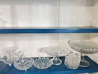 Shelf view showing all clear pressed glass pieces grouped together