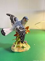 Front view of bird figurine showing coloration and floral base