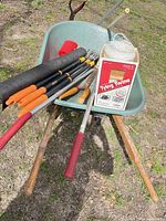 Wheelbarrow filled with assorted long-handled tools, twine box, scoop and fabric roll