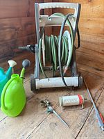Overall lot showing hose reel cart with hose, Gardena sprayer, spike sprinkler, watering cans, fittings