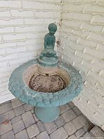 Full view of concrete fountain with figurine in corner setting