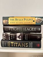 Spine view of all four hardcover books stacked showing titles and authors
