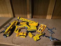 Group shot of seven yellow die-cast construction vehicles on tabletop