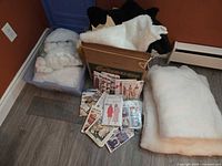 Overall lot: faux fur pieces in cardboard box, plastic bin with stuffing, stack of polyester batting, sewing patterns, ruler