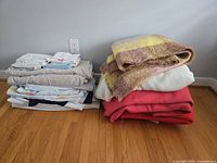 Two stacks of assorted blankets, throws, sheets