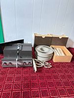 Optina 500 II projector with remote, power cord, two slide trays, stack loader box on red carpet