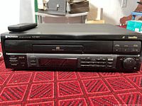 Front view of Pioneer CLD-S201 LaserDisc player with remote on top