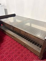 Side angle showing wood frame, glass top, lower slatted shelf, surface wear