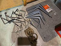 Overview of assorted shelf brackets and brass lion door knocker on floor