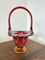 Front view of iridescent red and amber carnival glass basket with handle