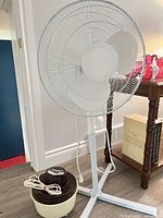 Full view pedestal fan beside table and humidifier placed at base