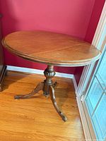 Full view of round wooden side table against wall