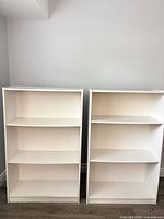 Front view showing both white bookshelves and overall condition