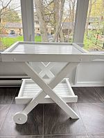 Full view of white wooden serving cart showing two tiers and wheels