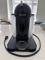 Front view of Nespresso Vertuo showing drip grid, power cord, and clear water tank