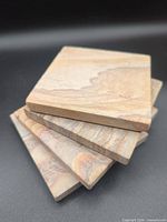 Stack of four square sandstone coasters showing top surface patterns