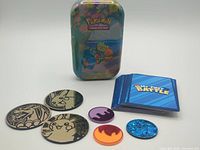 Mini tin, stack of My First Battle cards and seven Pokémon coins/tokens
