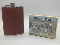 Hip flask and boxed playing cards side by side